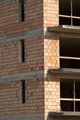 A large brick building is currently under construction, featuring numerous windows that allow for ample natural light to enter the space