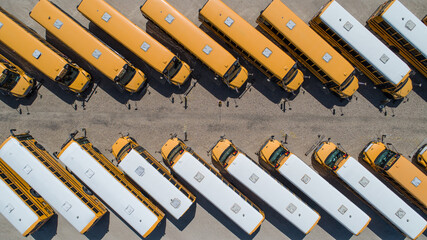 A row of yellow school buses are parked in a lot