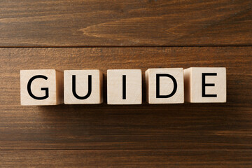 Word Guide made of cubes on wooden table, top view