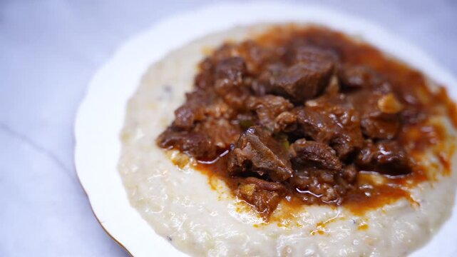 Traditional Turkish Hunkar Begendi food with creamy eggplant puree base. Made with tender meat, served on white plate. Turkish anatolia cuisine concept