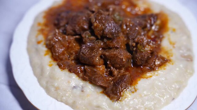 Traditional Turkish Hunkar Begendi food with creamy eggplant puree base. Made with tender meat, served on white plate. Turkish anatolia cuisine concept