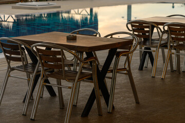 Charming outdoor dining setup by a tranquil swimming pool in the evening glow