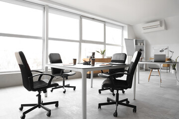 Interior of light conference hall with tables, window and armchairs