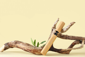 Mascara with branch and green twig on light yellow background. Eco style concept