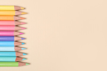 Set of colorful pencils on beige background