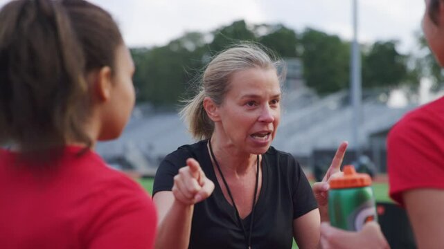 An enthusiastic coach instructs her students athletes at practice