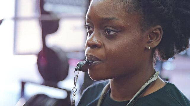 Female coach blows a whistle during a practice