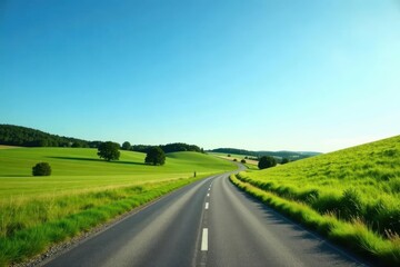 Fototapeta premium Asphalt Road Winding Through Lush Green Rolling Hills Under a Vivid Blue Sky