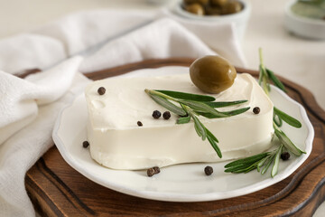 Plate with tasty feta cheese, olive, rosemary and peppercorn on white background