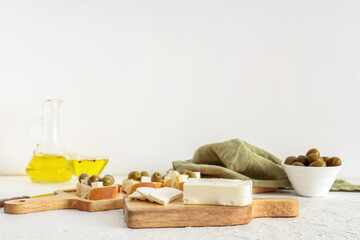 Wooden board with tasty feta cheese on white background