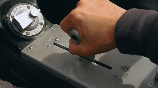 The hand of the pilot of a small training aircraft grabs the engine control lever and sets the maximum speed during takeoff. Close-up of the throttle inside the cockpit