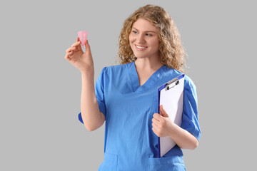 Female doctor with menstrual cup and clipboard on grey background