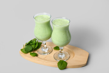 Glasses of fresh spinach smoothie on grey background
