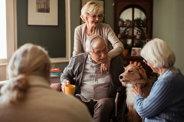 Happy senior friends spending time together with dog at home