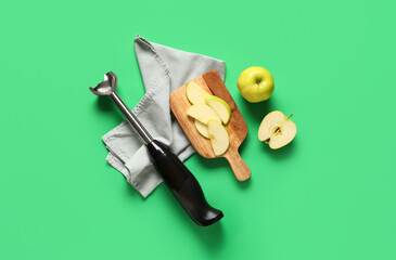 Blender, napkin, wooden tray and apples on green background