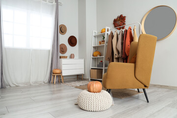 Fototapeta premium Interior of dressing room with coat rack, armchair and pumpkins