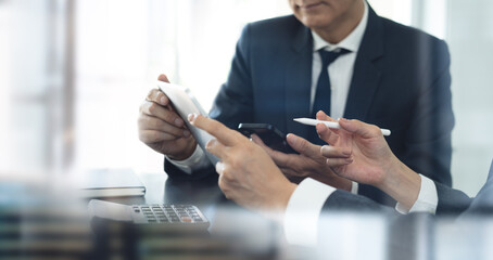 Businessman having a discussion with colleague, working together in office. Two asian business people using digital tablet at meeting. teamwork and collaboration