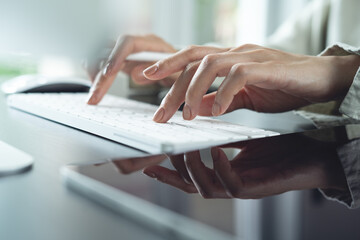 Closeup, business woman hand typing on computer keyboard, with digital tablet on office table, online working, surfing the internet, searching the information, remote work, business background