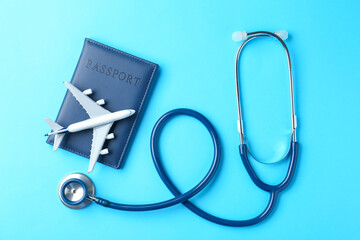 Medical tourism. Stethoscope, passport and plane model on light blue background, flat lay