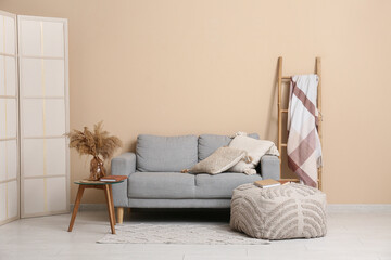 Interior of stylish room with grey sofa, wooden ladder and coffee table