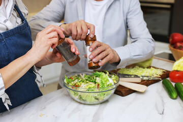 Senior couple cooking together at table in kitchen, closeup