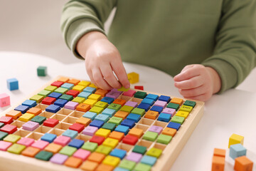 Fototapeta premium Motor skills development. Little boy playing with Times table tray indoors, closeup