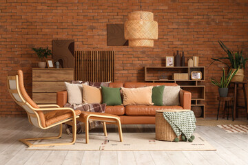 Interior of living room with leather sofa, armchair, wicker basket and shelving unit
