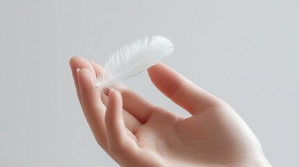 Fototapeta premium Gentle touch of a hand holding a feather minimalist indoor scene serenity