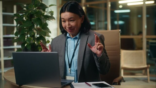 Successful happy Asian Korean Chinese Japanese woman hope wish crossed fingers good luck ask for victory working laptop win female girl businesswoman business office indoor winner celebrate employer