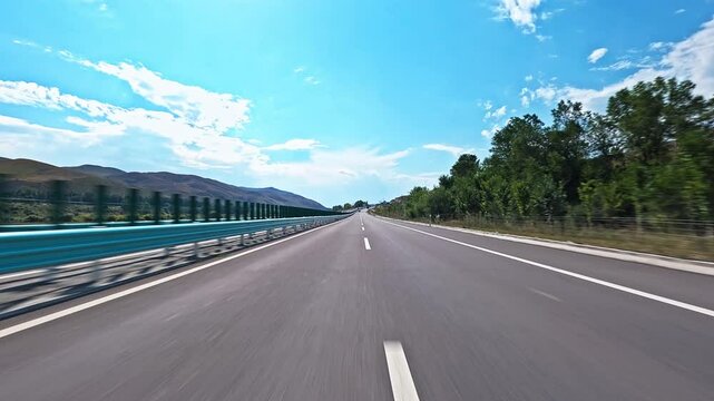 Open road stretches into the distance under the clear blue sky with clouds. Driving a car on country highway.