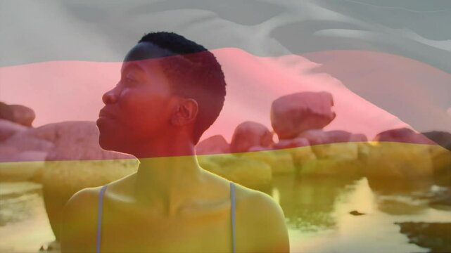 At beach, woman holding flag with animation blending into sunset background - Powered by Adobe