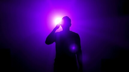 Silhouette figure holding flashlight in dark purple light