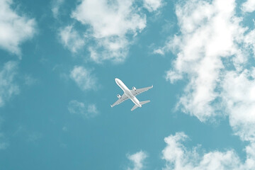 A realistic white airplane soars against a vibrant blue sky dotted with white clouds