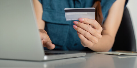 Digital Payments and Credit Management. Close-up of a hand holding a credit card over a laptop, reflecting modern finance solutions.
