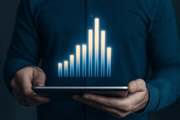 Person holding digital tablet displaying glowing bar chart representing business data growth and performance metrics