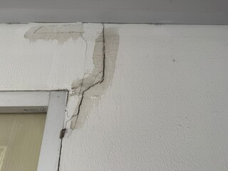 The cracks on the wall near the door frame indicate the impact of an earthquake. The wall has water stains around the cracks, suggesting damage that may have resulted from structural movement or stron