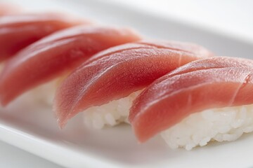 A close-up of fresh maguro (tuna) nigiri sushi, expertly sliced fish atop seasoned sushi rice, isolated on a white background.