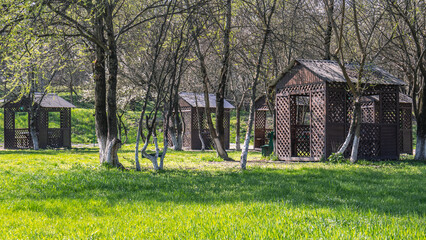 Wooden gazebos for relaxing in the park. A place for a family vacation in nature. A place for cooking shish kebab. Outdoor recreation in spring. Flowering trees.