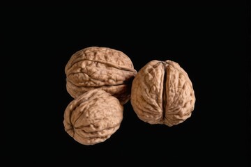 Fresh and healthy walnuts arranged in a triangular formation on black background, shot from a slightly angled perspective.