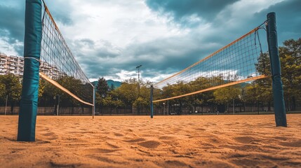 A volleyball on a soft, sandy court under an overcast sky, with no players in sight, creating a peaceful, yet athletic mood.