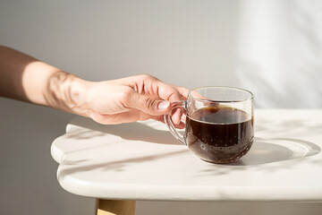 Woman Having Coffee in Glass Mug Morning Sunlight Indoors at Home. Enjoying Hot Aromatic Drink for Everyday Life.