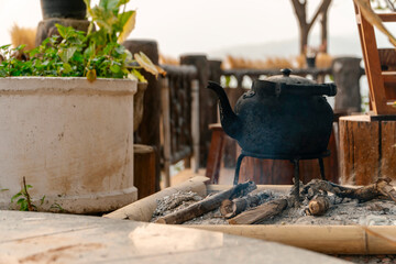 A cast iron teapot stands outside on the fire and the water steams