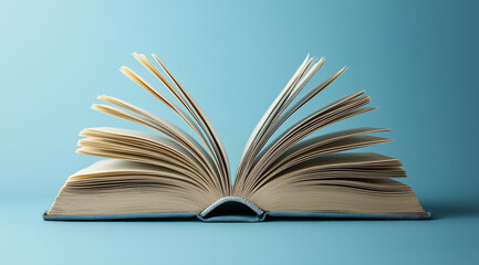 Fototapeta premium An open book with pages turning, representing knowledge and learning on a blue background.Concept World Book Day