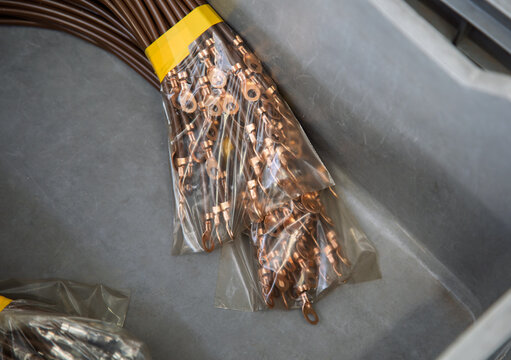 Cable Terminal Ends , electrical cable connections pack, cooper brass end with a hole, custom coaxial cable, two packs of cables wrapped in plastic in an industrial bin.