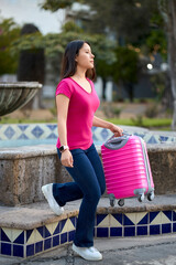 Confident young traveler walking with pink suitcase outdoors