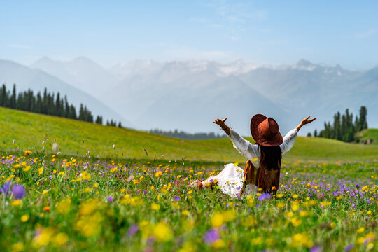 Young woman traveler relaxing and enjoying beautiful Scenery landscape with colorful flowers in Kalajun grassland of Xinjiang in summer - Powered by Adobe