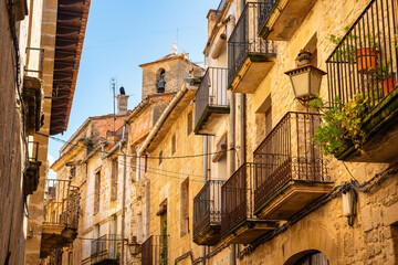 Beautiful stone balconies and metal grilles with pots and flowering plants in Teruel, Matarrana, Aragon.
