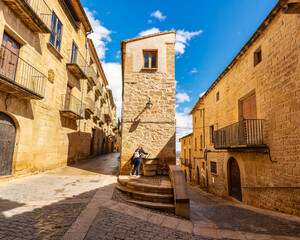 Tourist woman drinking fresh water from a public fountain in the medieval streets of Calaceite, Teruel.