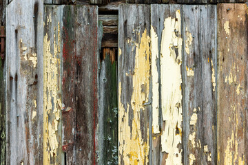 Paint peeled off the weathered wooden boards showcases a rich tapestry of history and time on this aged structure.