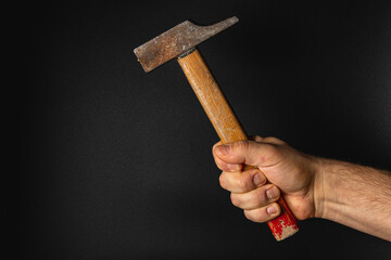 Holding a worn hammer against a dark backdrop